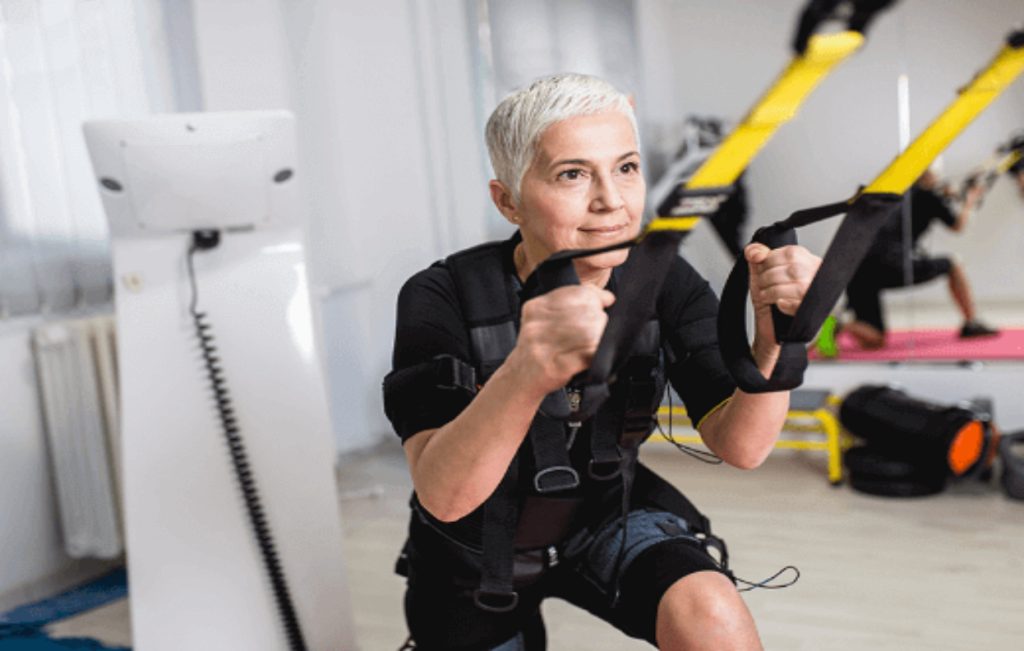 Woman in SQAI suit doing a TRX workout